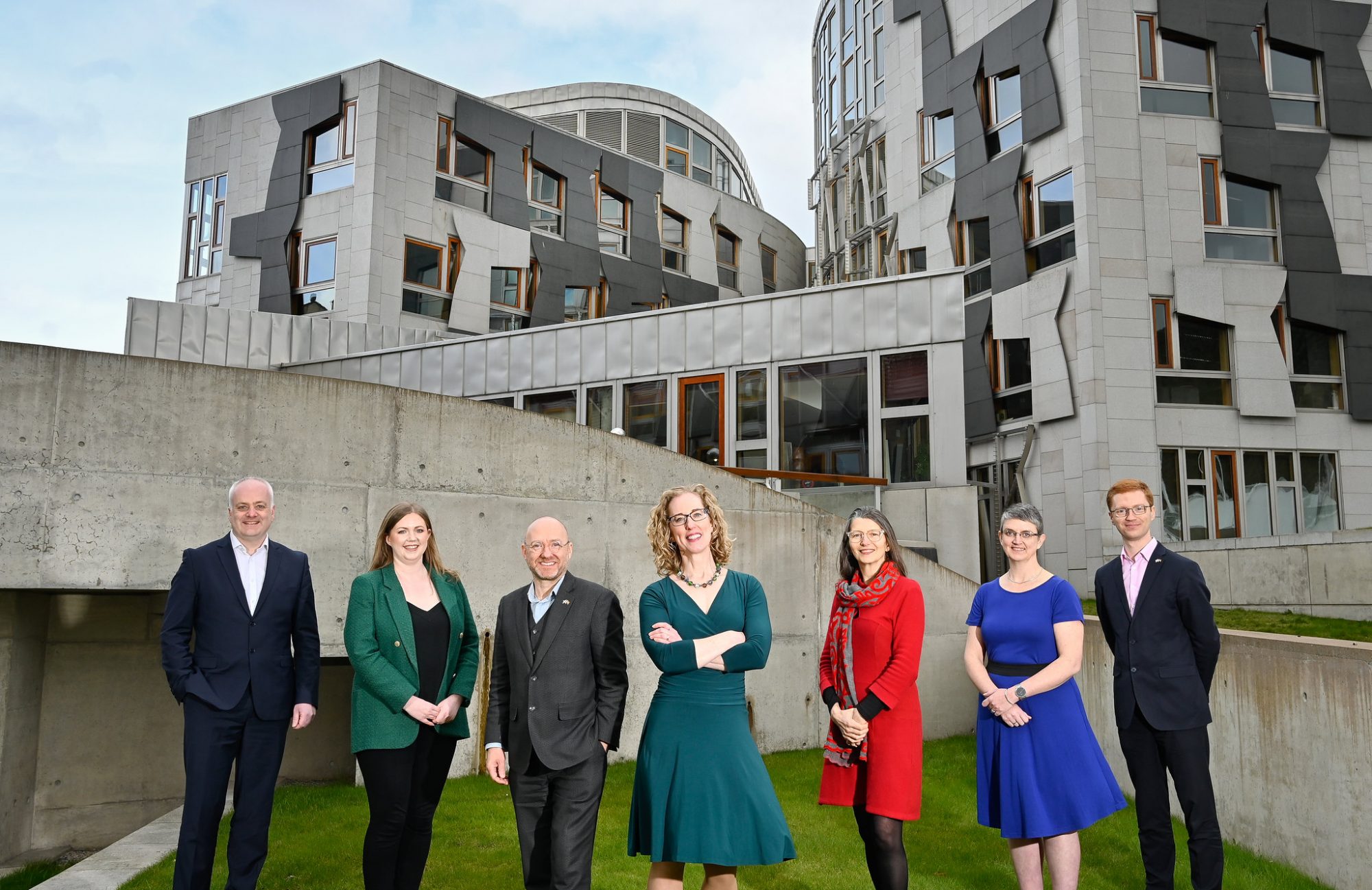 7 people standing outside the Scottish Parliament building at Holyrood